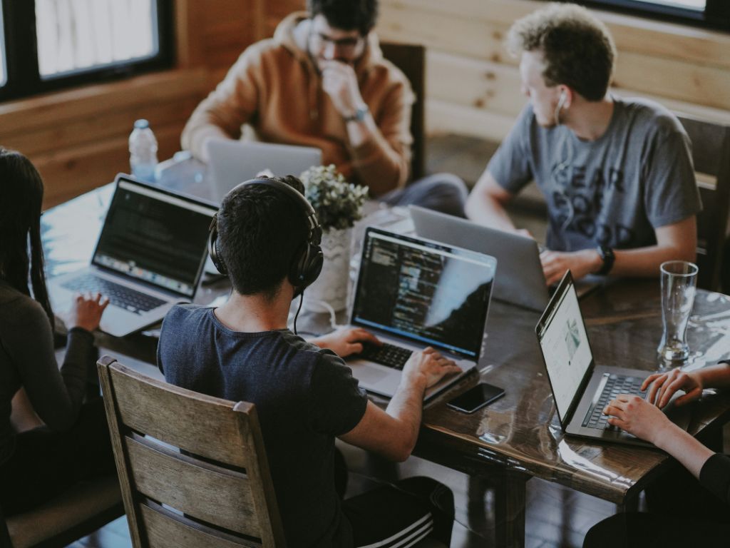 A table of colleagues working together with laptops when blogging for business.